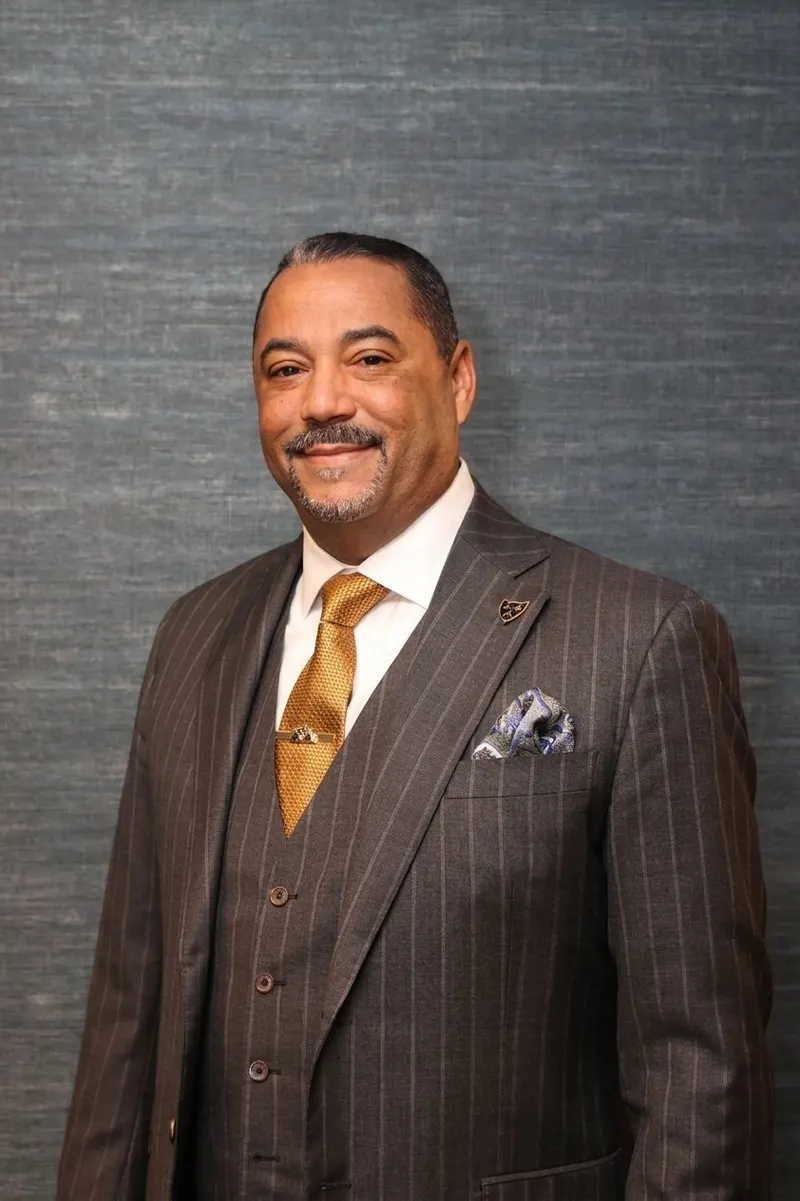 Studio portrait of Eric Hardy in a pinstripe suit and gold tie